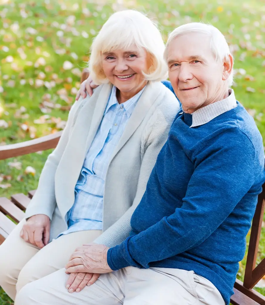 An older couple smiling together on a park bench